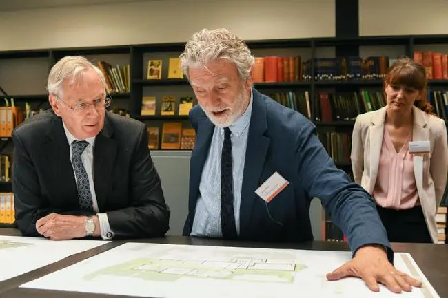 Three people look at building plans for the Hold