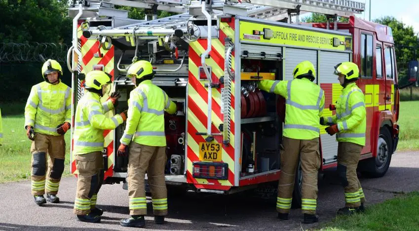 Five firefighters attend to equipment on a fire appliance
