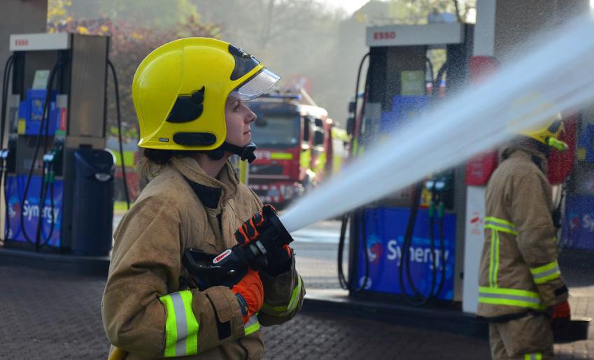 A firefighter uses a hose reel at an incident