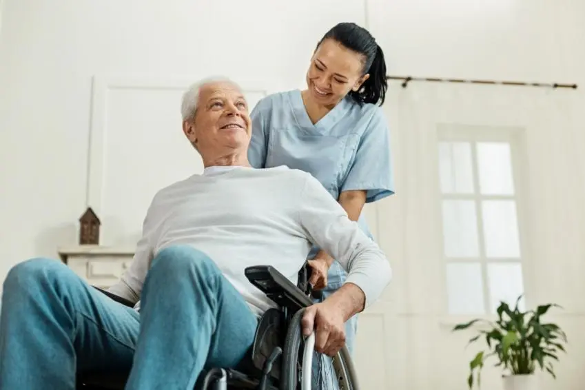 Older man in wheelchair and health worker