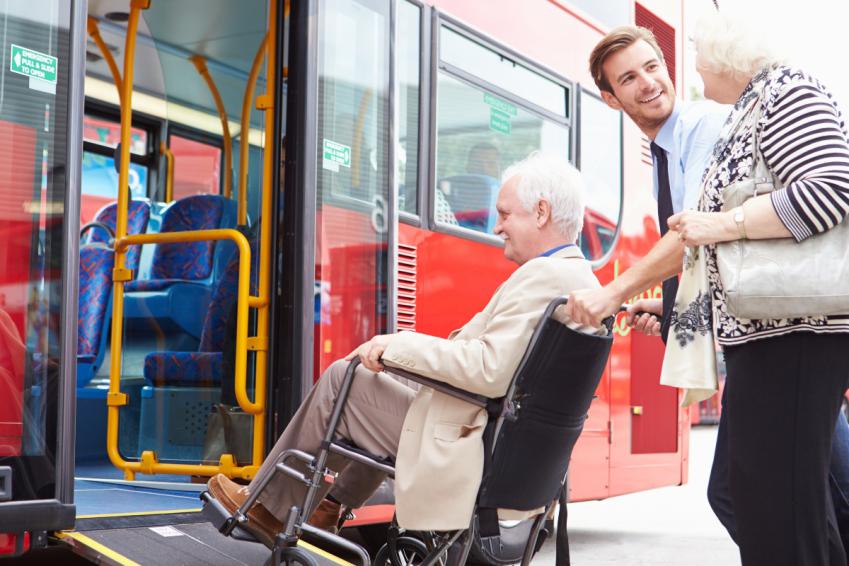 Person in a wheelchair being assisted on board a bus.
