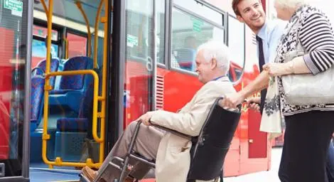 Person in a wheelchair being assisted on board a bus.