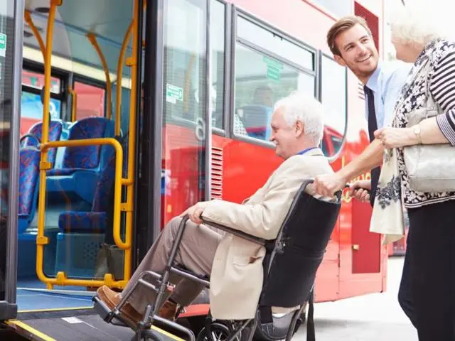 Person in a wheelchair being assisted on board a bus.