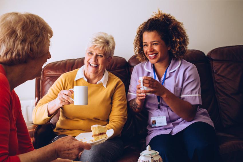 Women and healthcare worker enjoying tea and cake