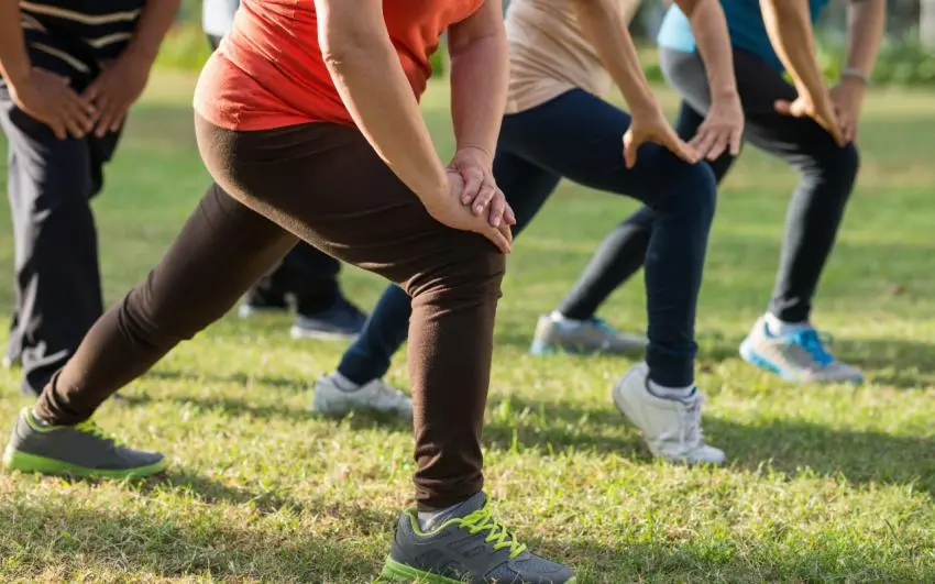 Group of people doing lunges in a park