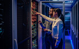 Two workers are inspecting a computer server