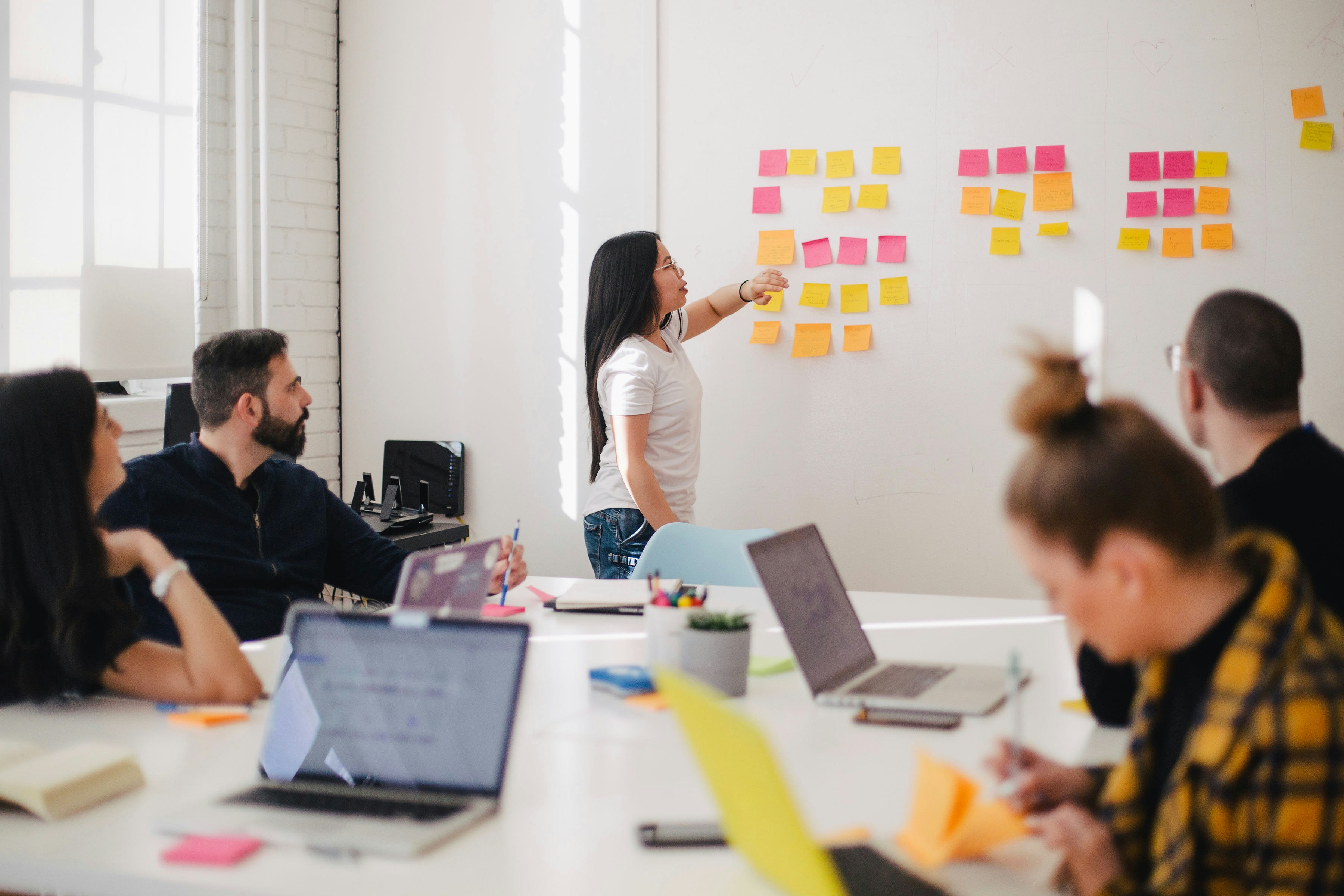 group of men and women  in board room looking a numerous post its on a wall