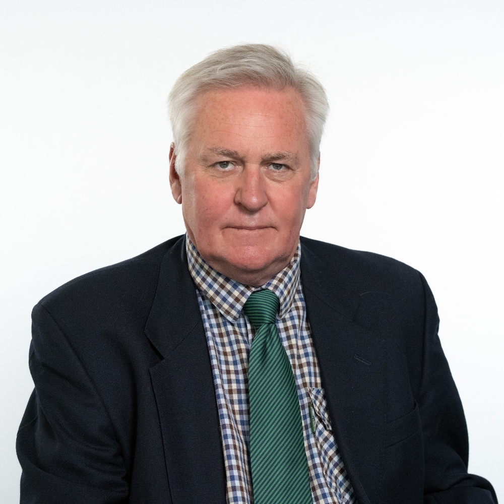 Cllr John Matthews wearing suit jacket, checked shirt and green tie