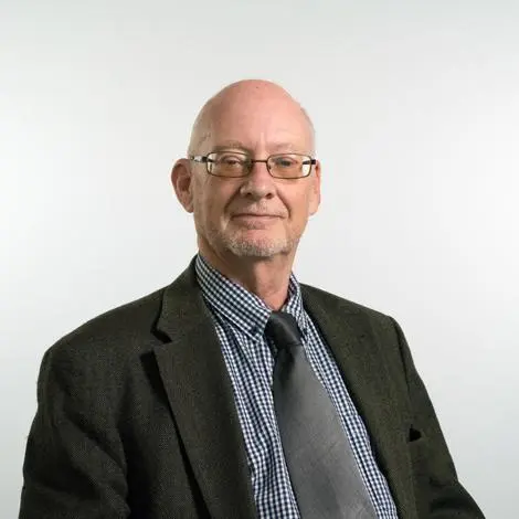 Councillor John Nunn wearing a dark grey jacket checked blue and white shire and grey tie smiling