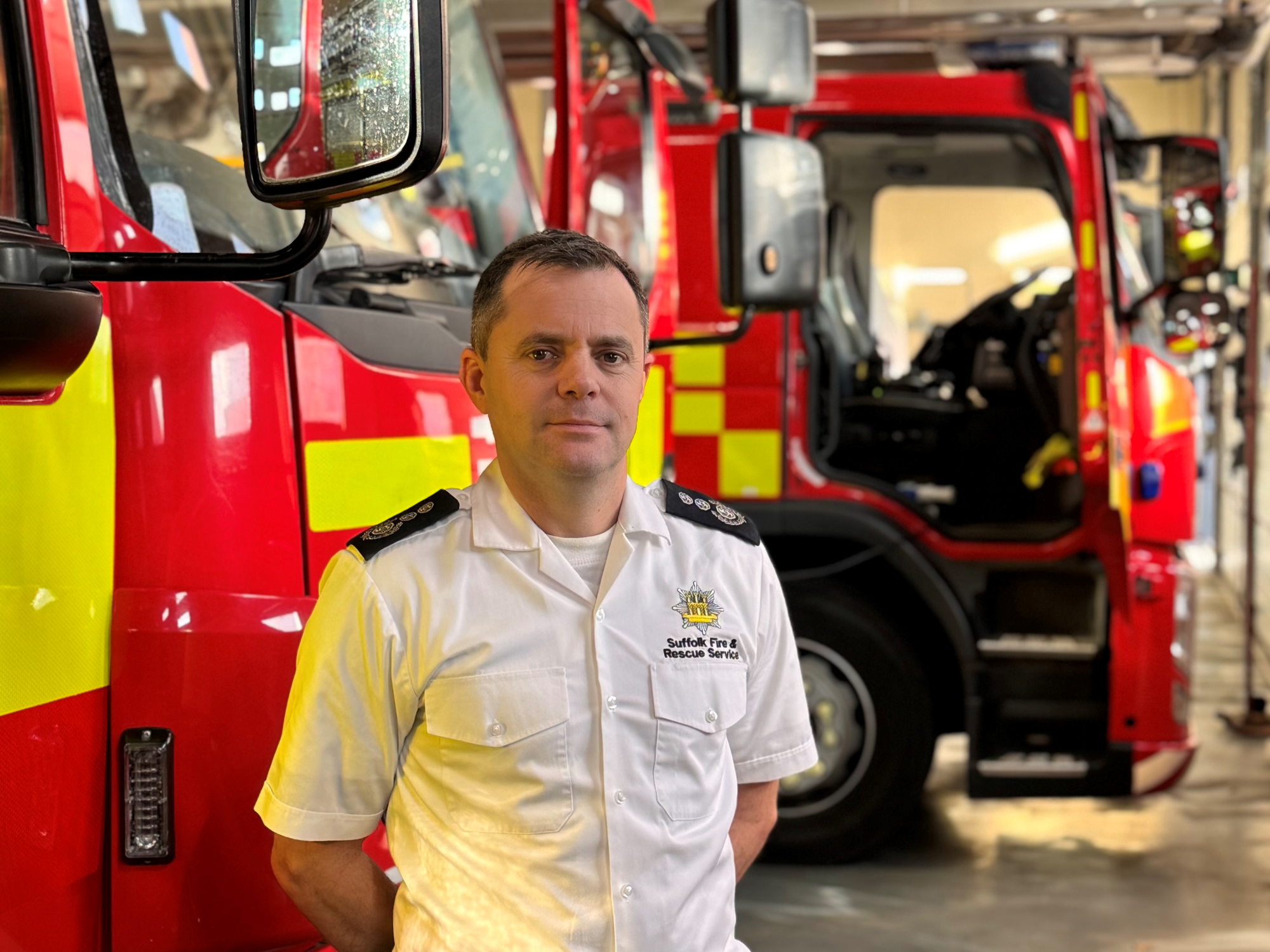 Jon Lacey, Chief Fire Officer in front of two fire engines
