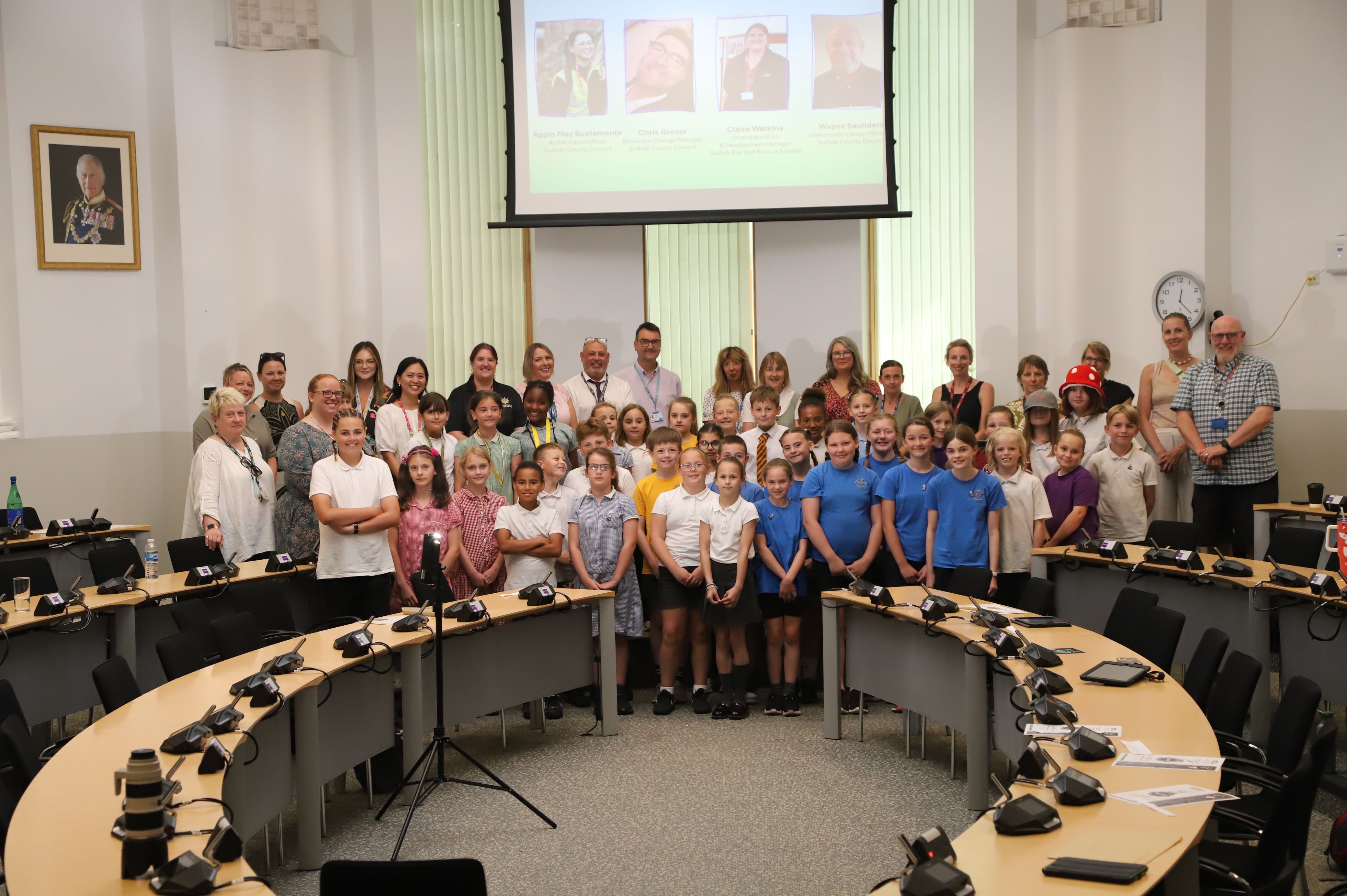 A large group of children and adults in the council chamber.