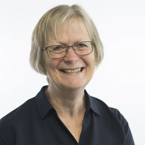 Image of Judy Cloke wearing a black blouse with dark rimmed glasses and short blonde hair