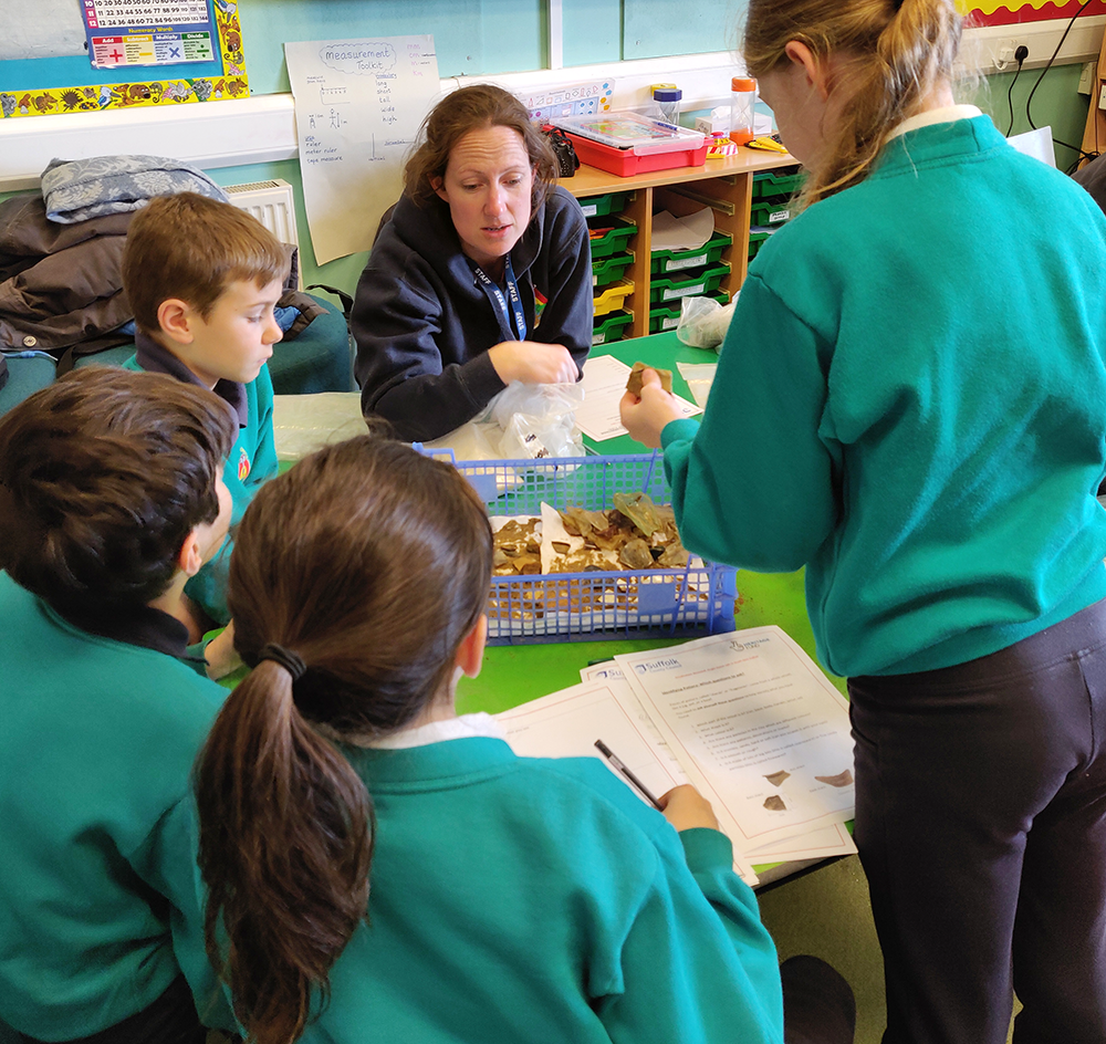 teacher looks at artefacts with four primary school children