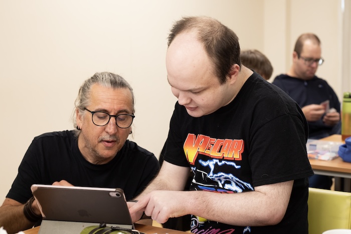A person with learning disabilities looking at a tablet with a person supporting them