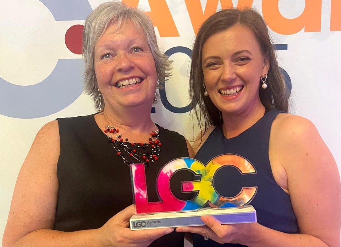 Beverly Davies and Ellie Coleby holding a trophy shaped with the letters LGC