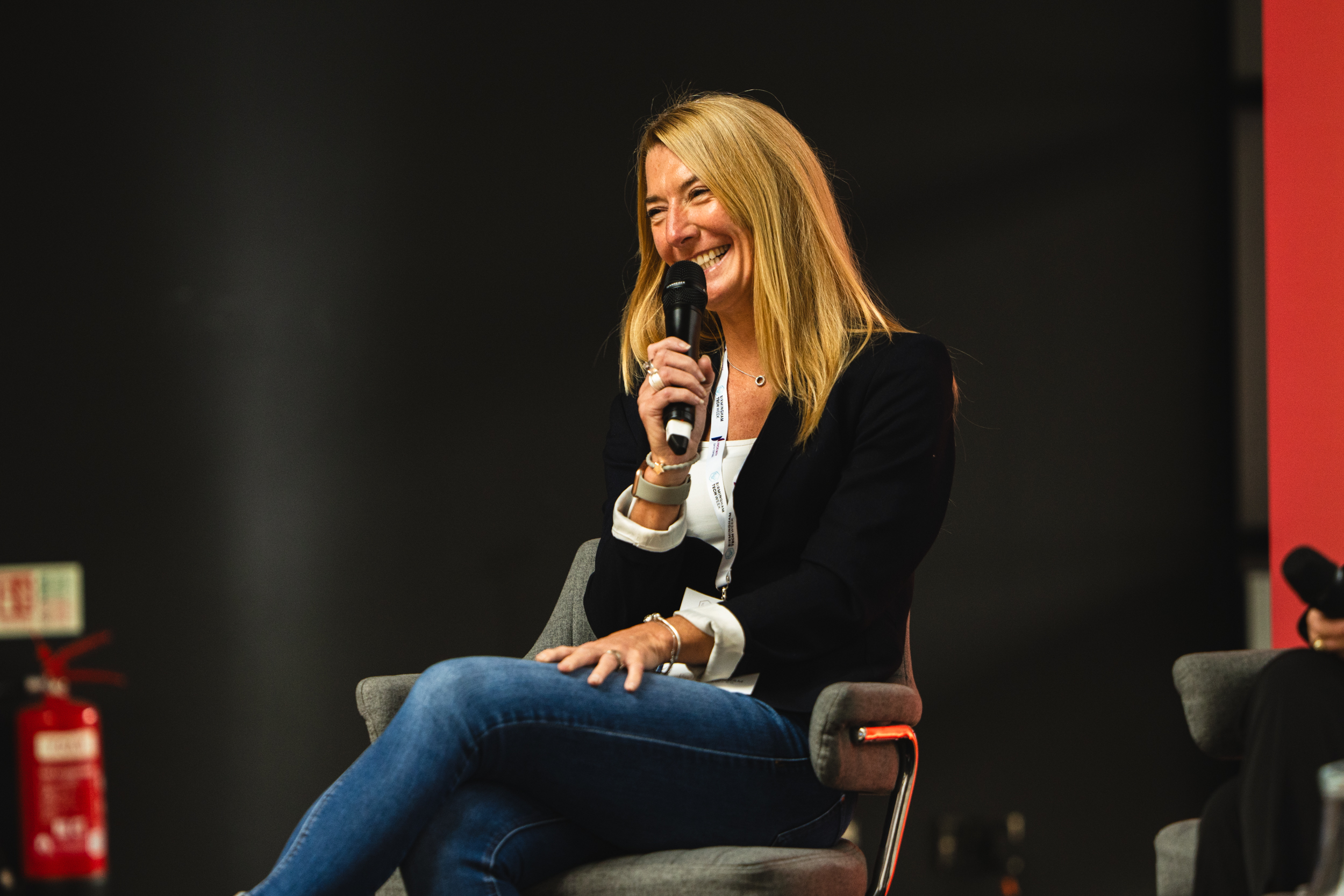 Lisa Perkins, Chair of the Suffolk Business Board, sitting on a stage with a microphone
