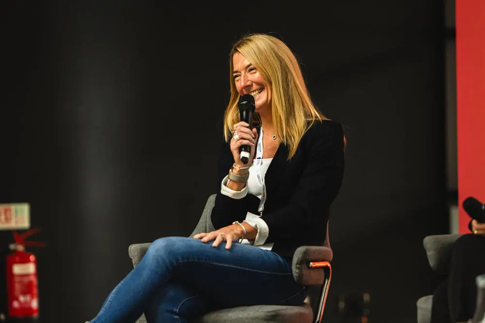 Lisa Perkins, Chair of the Suffolk Business Board, sitting on a stage with a microphone