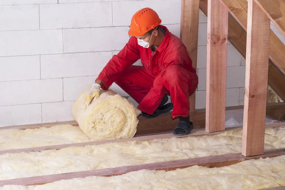 a worker lays loft insulation