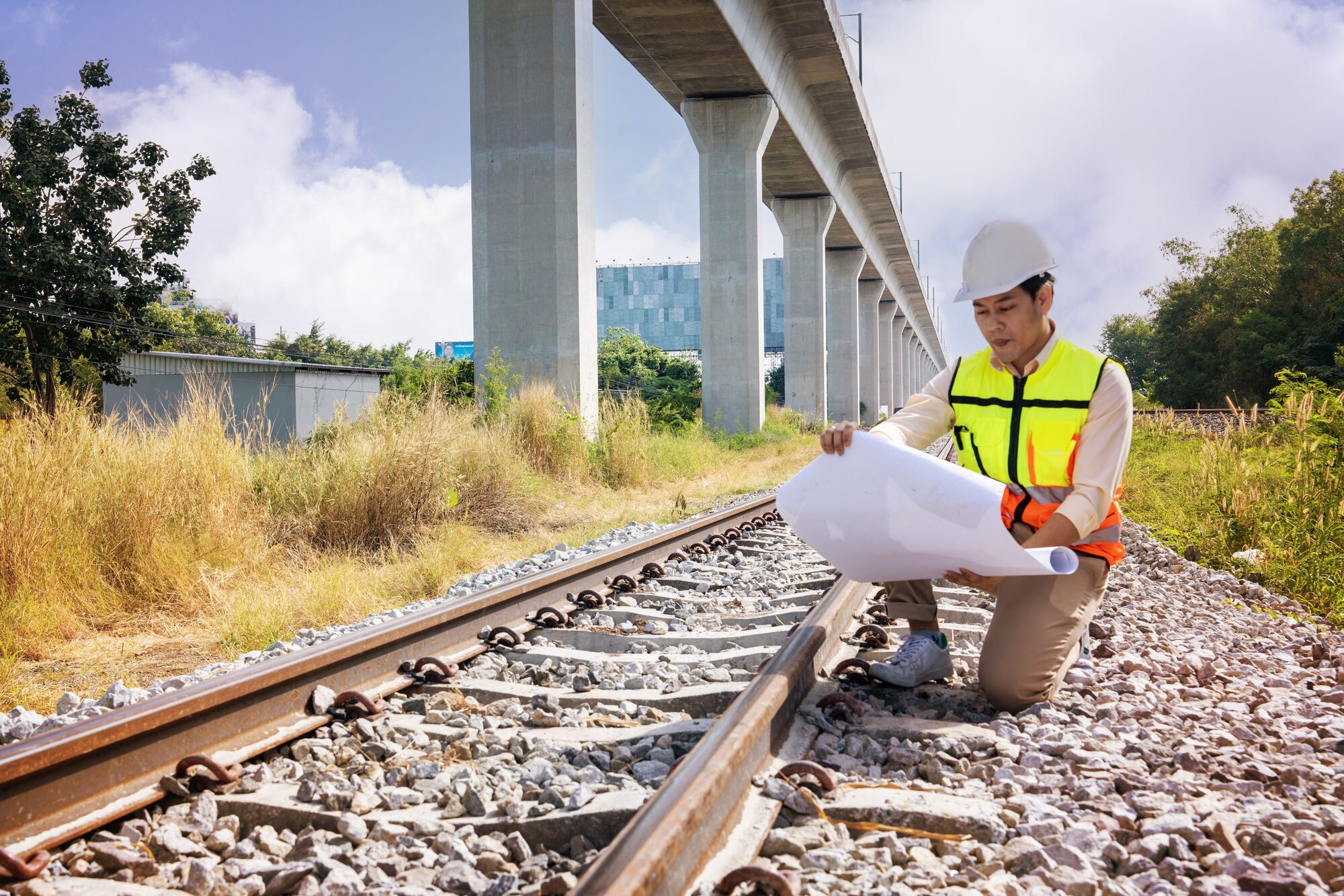 An engineer wearing a hard hat is sat inspecting quality railroad tracks