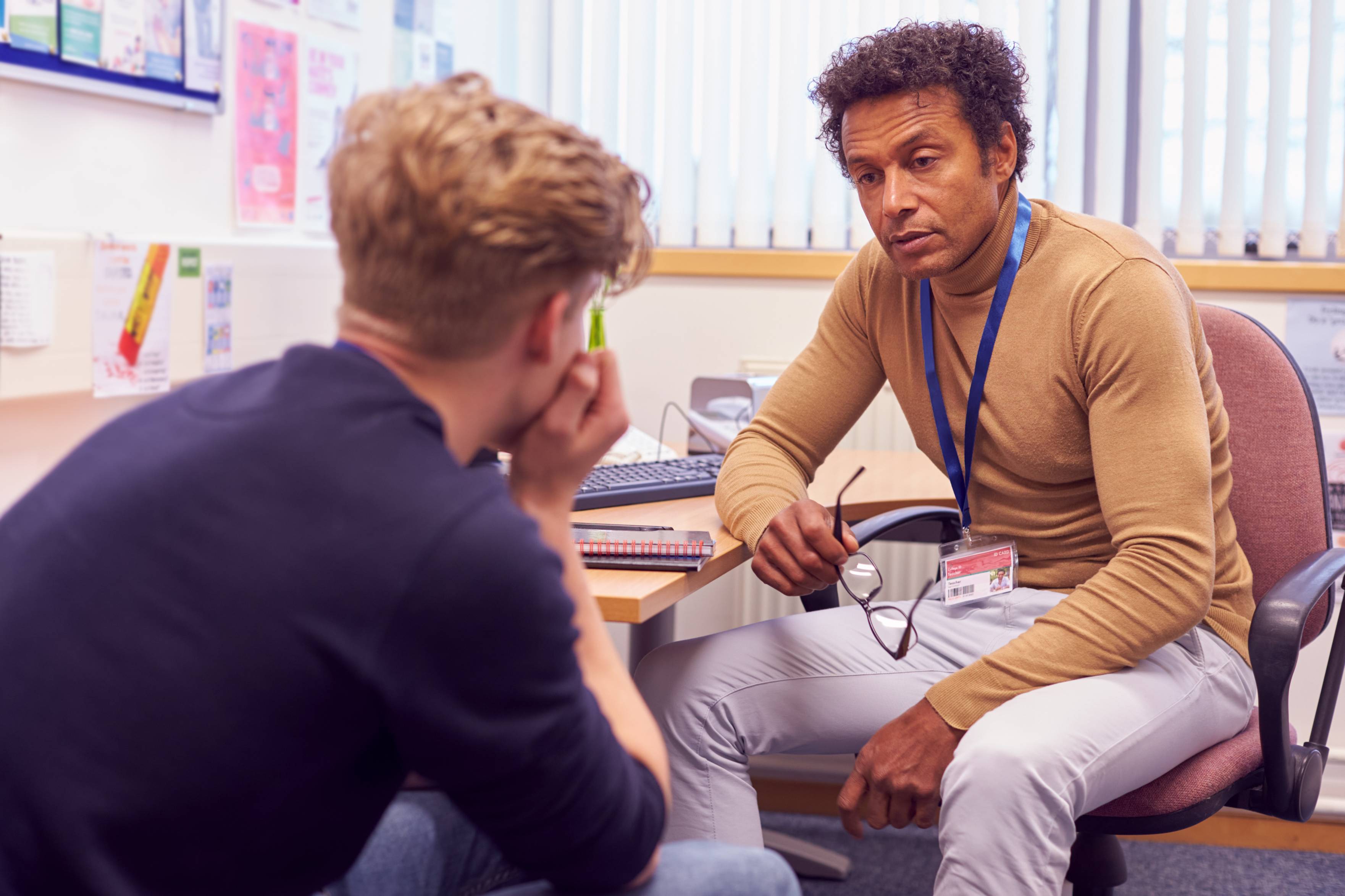Mental health professional or teacher talking to teenage boy