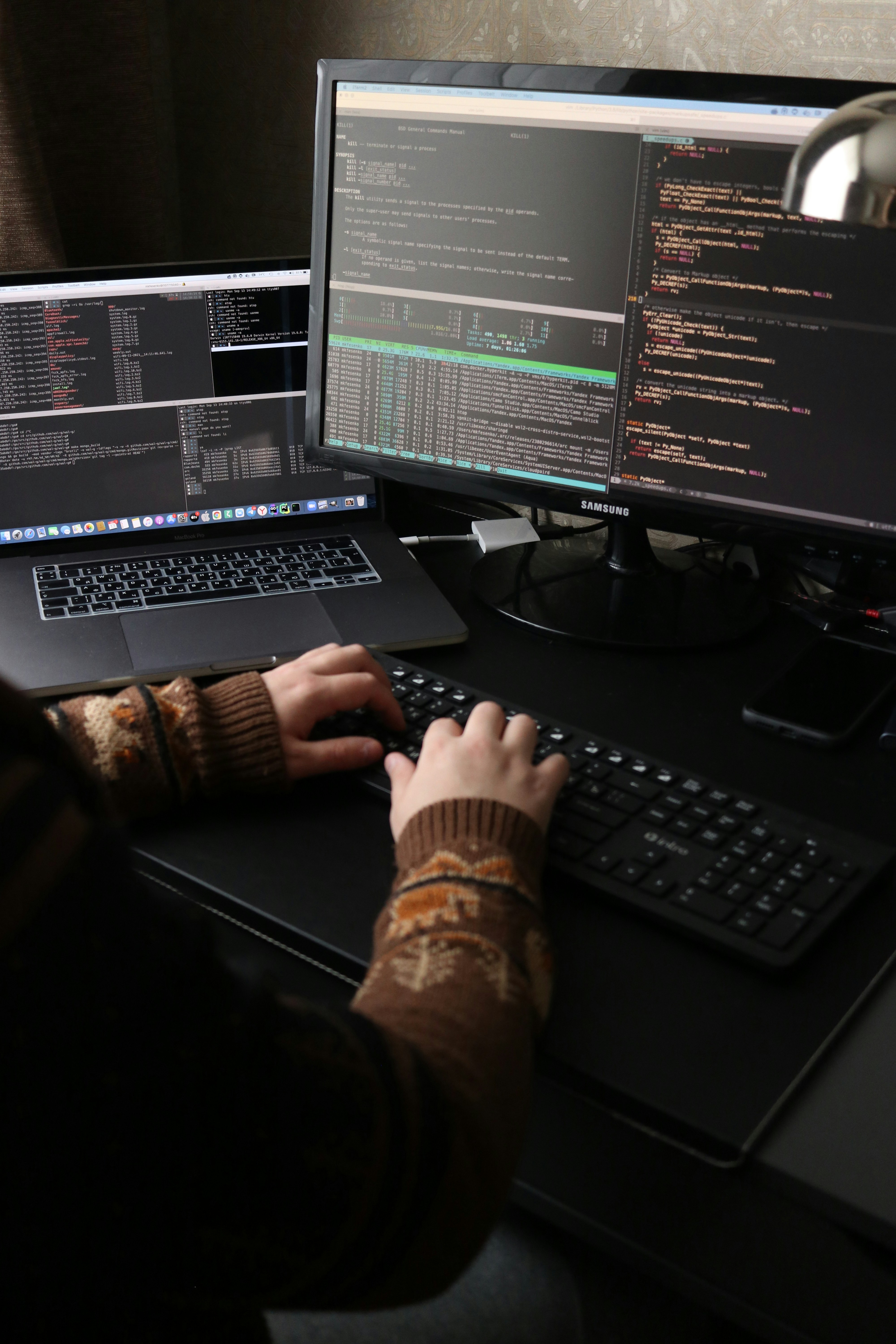 view of person's hands using a keyboard entering data which is displayed on two monitors