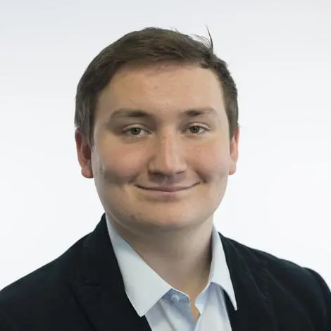 Nathan Wilson, smiling. Short brown hair, wearing white shirt and black suit jacket.