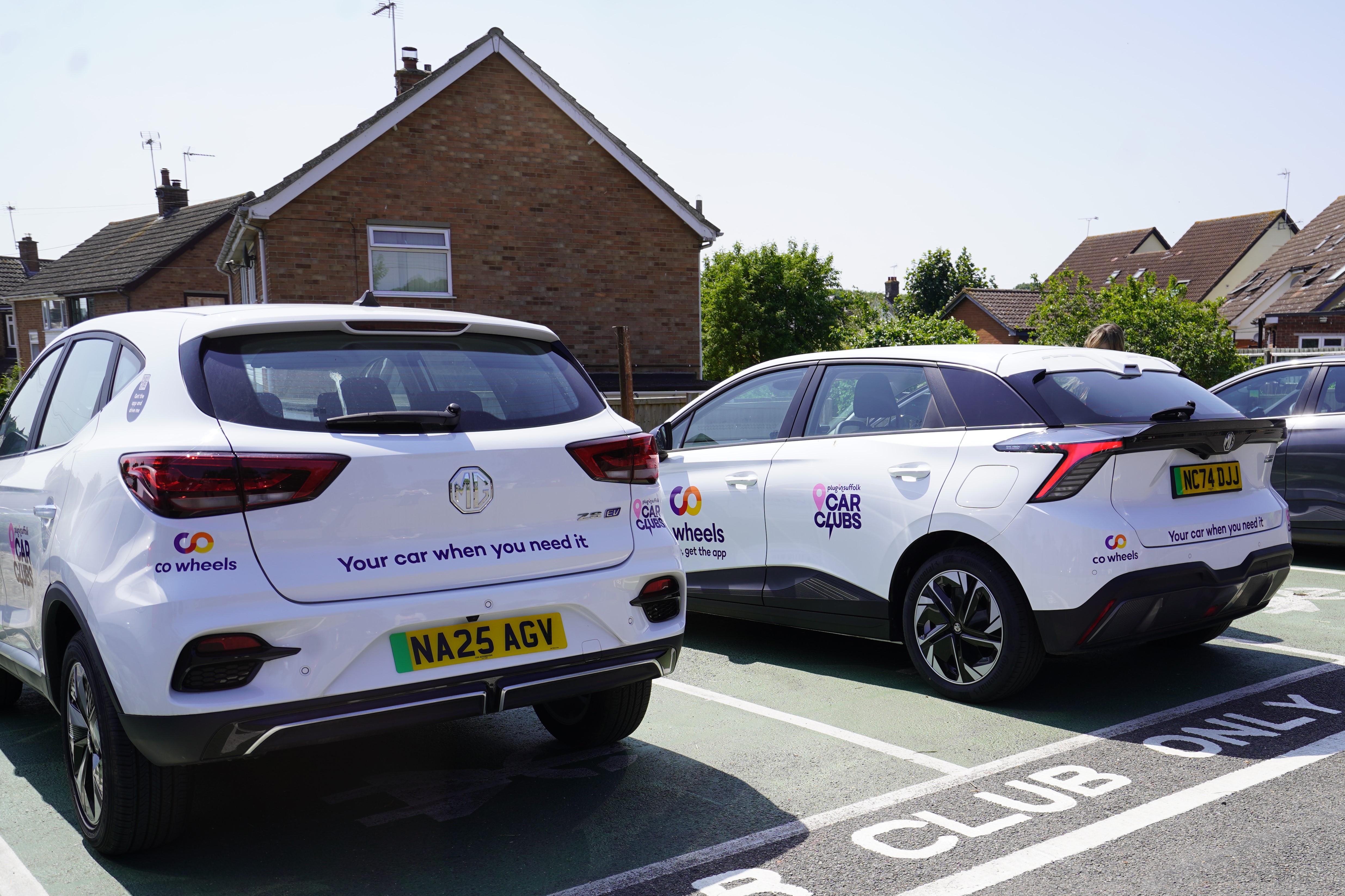 Two white electric MG vehicles parked in the Needham Market car club spaces. 