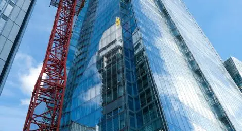 Photograph of construction happening on a skyscraper in a city