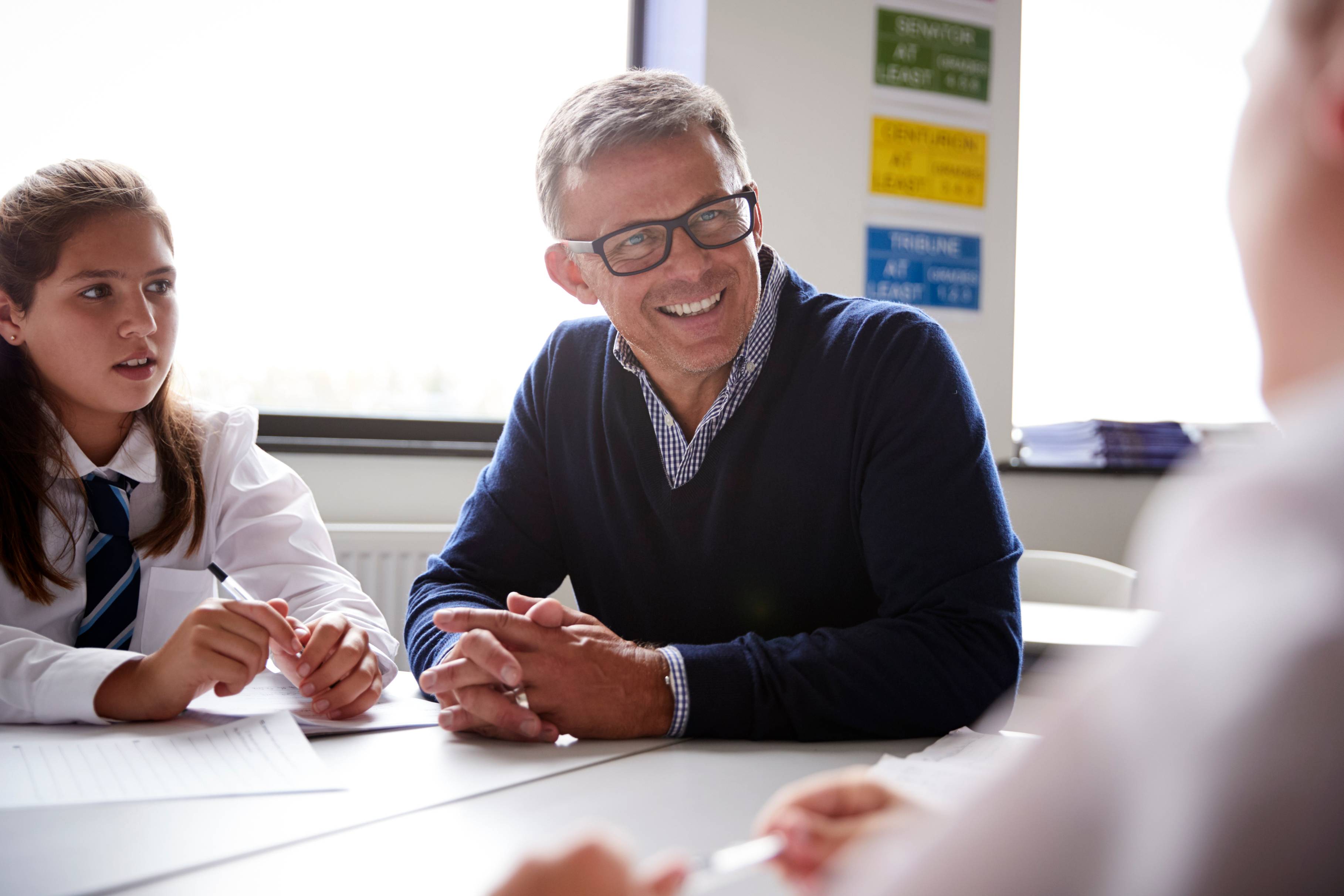 Older male teacher sitting and talking to his students