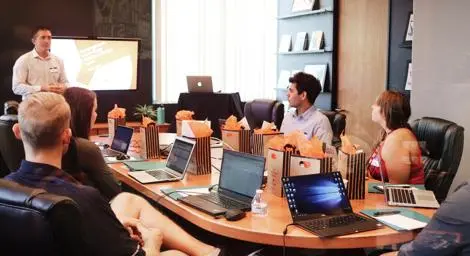 Man presenting to men and women in an office. 