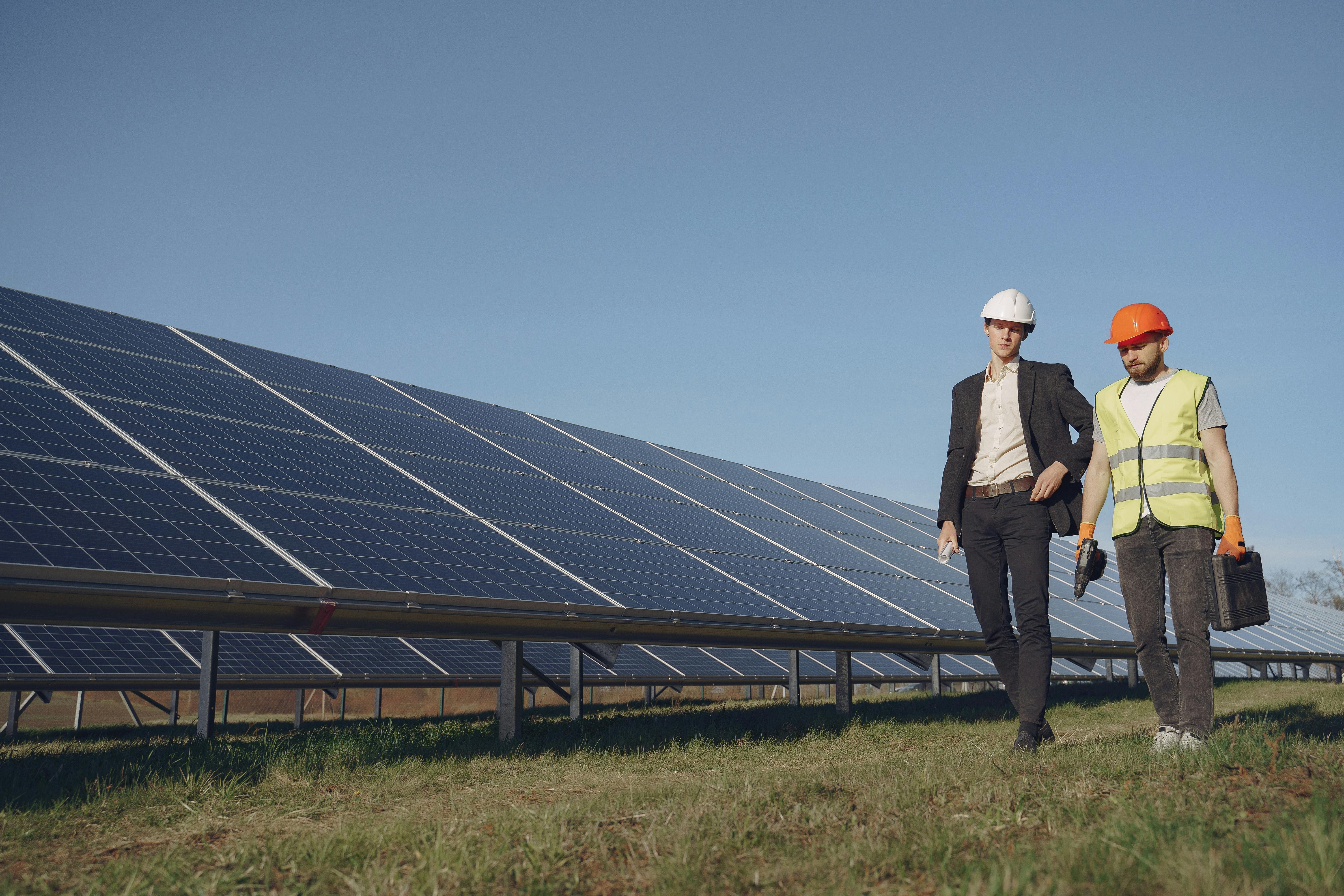Two construction workers walking in front of solar panels