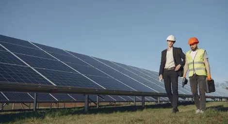 Two construction workers walking in front of solar panels