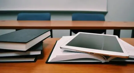 books stacked and laying open with an ipad sitting on top of the open book