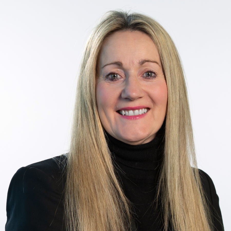 June Mummery wearing a black suit jacket with a black roll neck jumper and long blonde hair