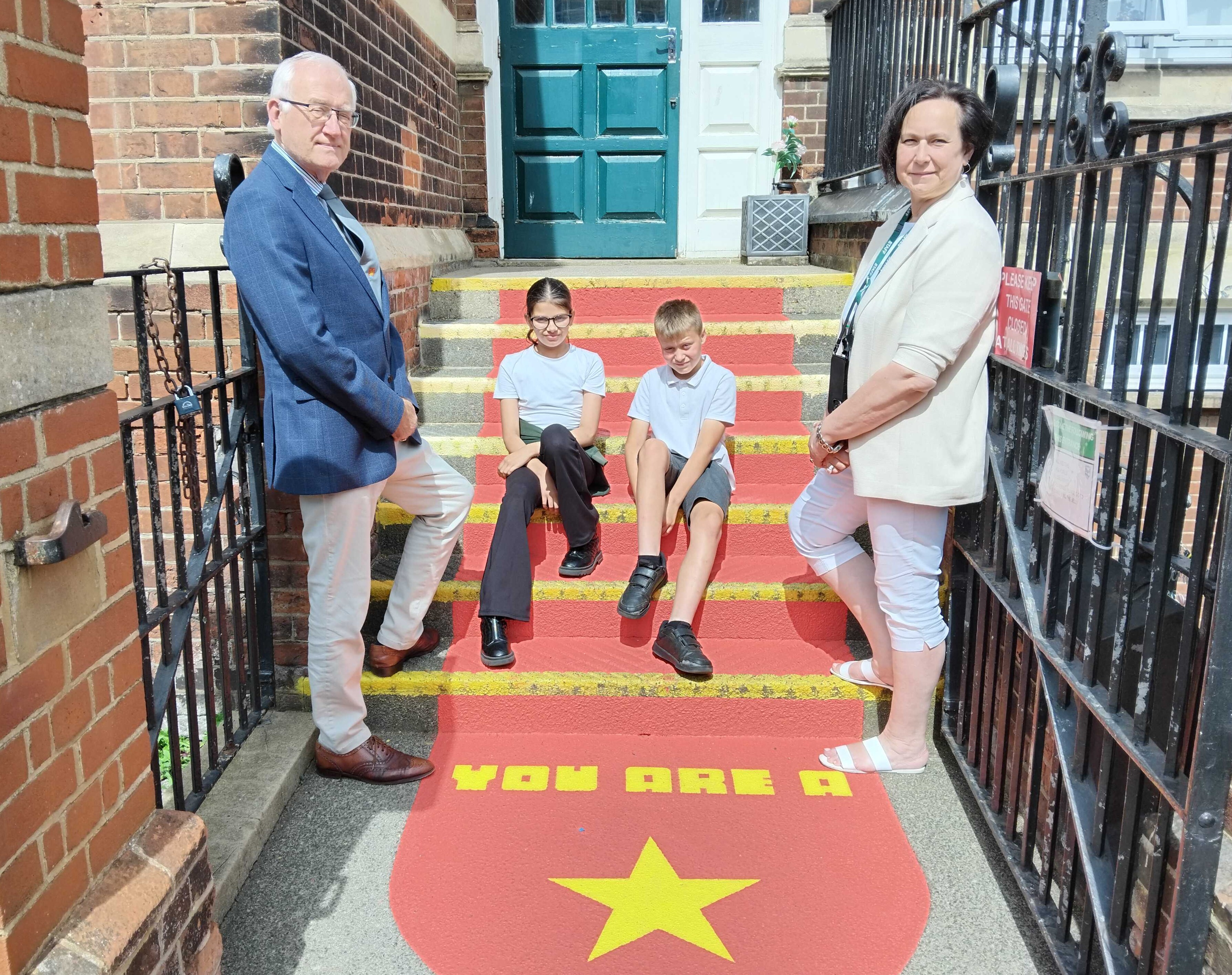 A boy and a girl and a man and a woman on a red-painted step with 'You Are A Star' painted in yellow.