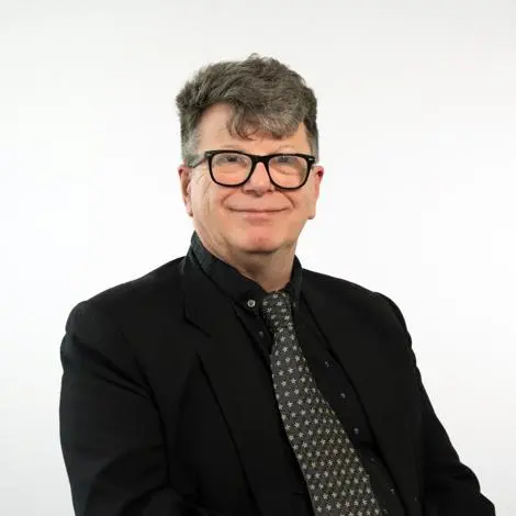 Councillor Robin Baxter-Ayling wearing a black jacket and shirt with a grey patterned tie smiling