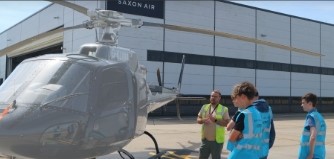 Three people standing around a helicopter 