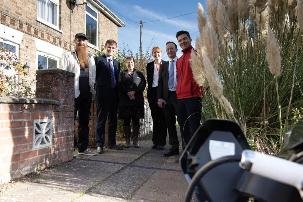 six people pose for a photograph outside a house