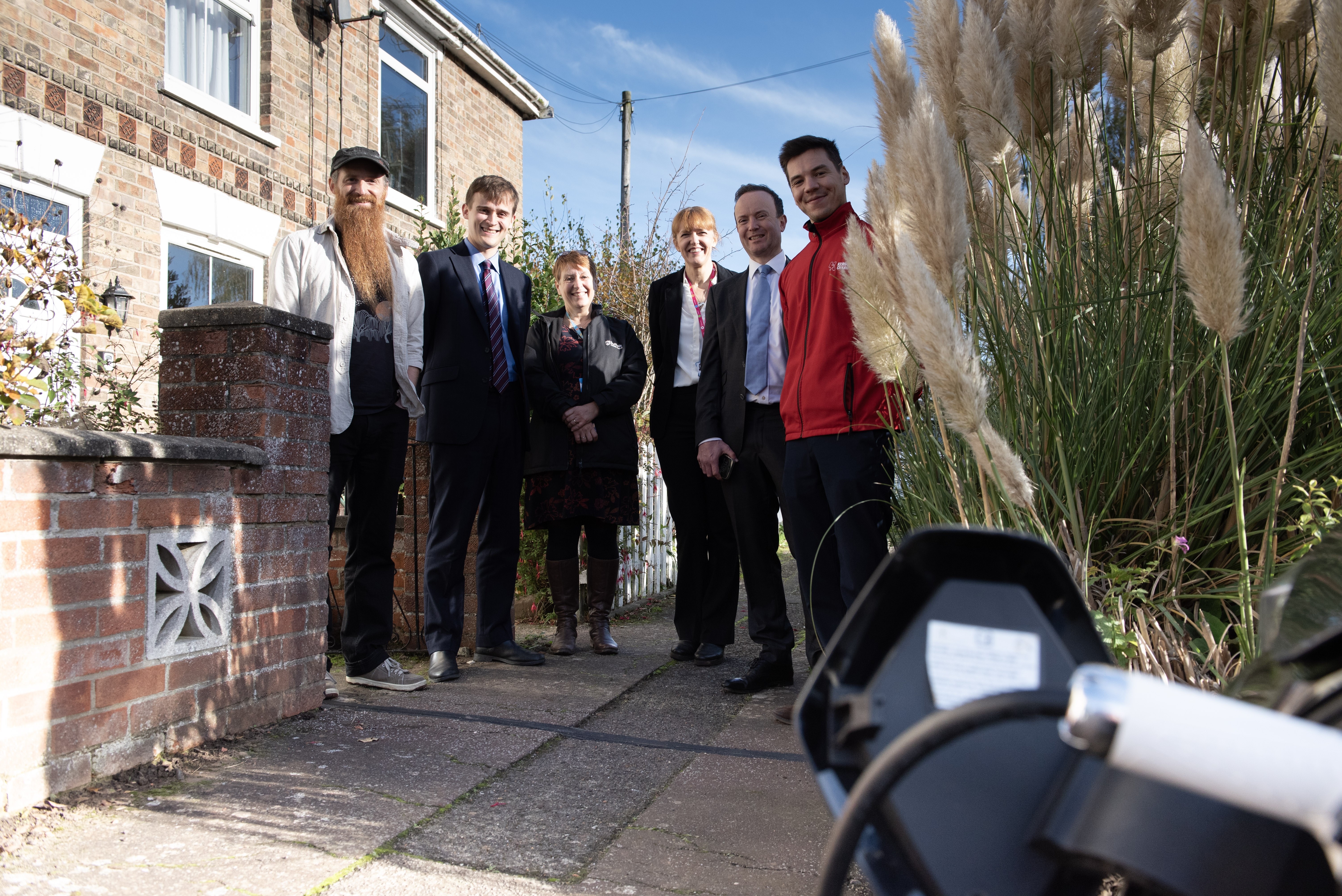 six people pose for a photograph outside a house