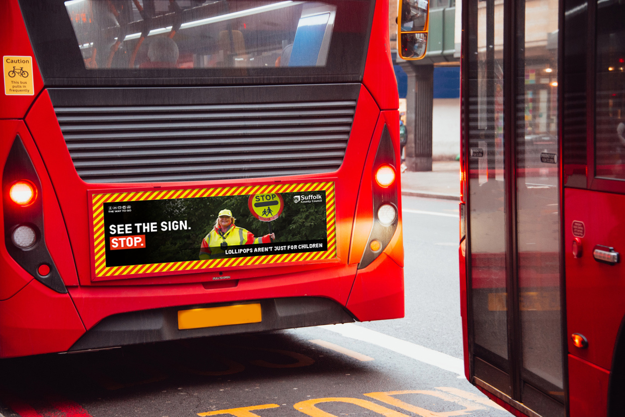 A bus with a crossing patrol officer with a Stop handheld sign and caption of 'See The Sign Stop'.