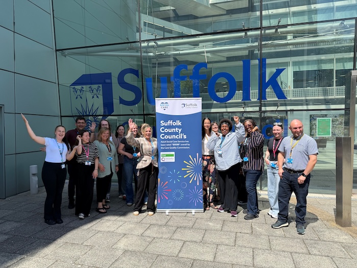 The Adult Social Care Social Work team standing with a banner about the CQC "good" review. 