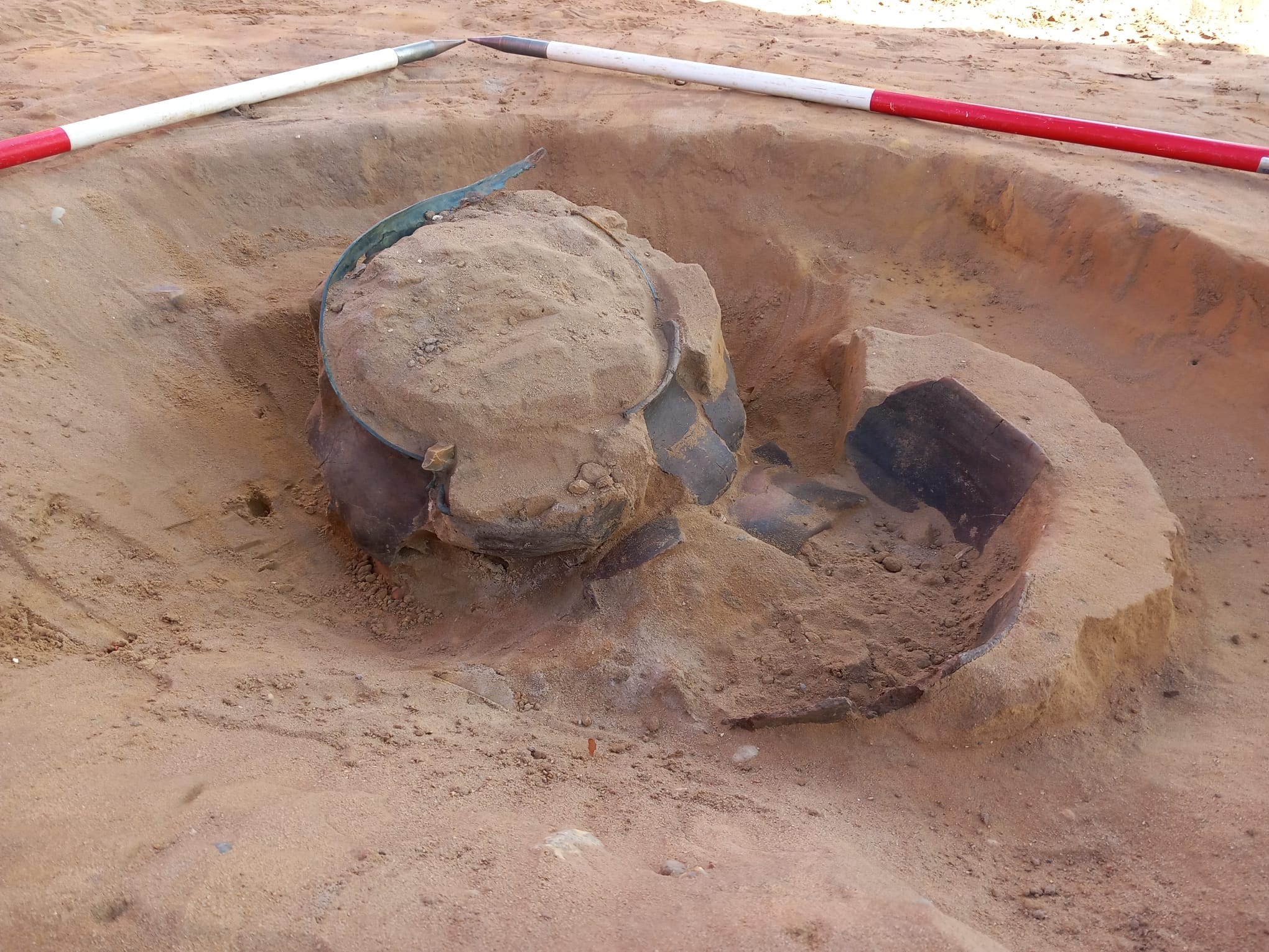 a whole but broken bowl protruding from sandy soil