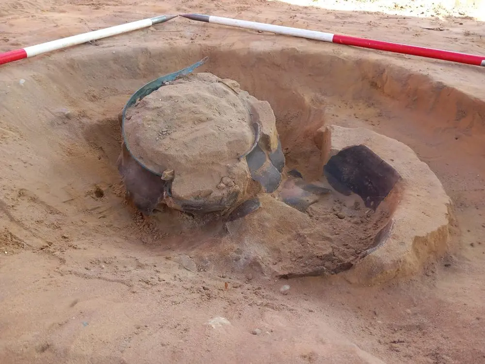 a whole but broken bowl protruding from sandy soil