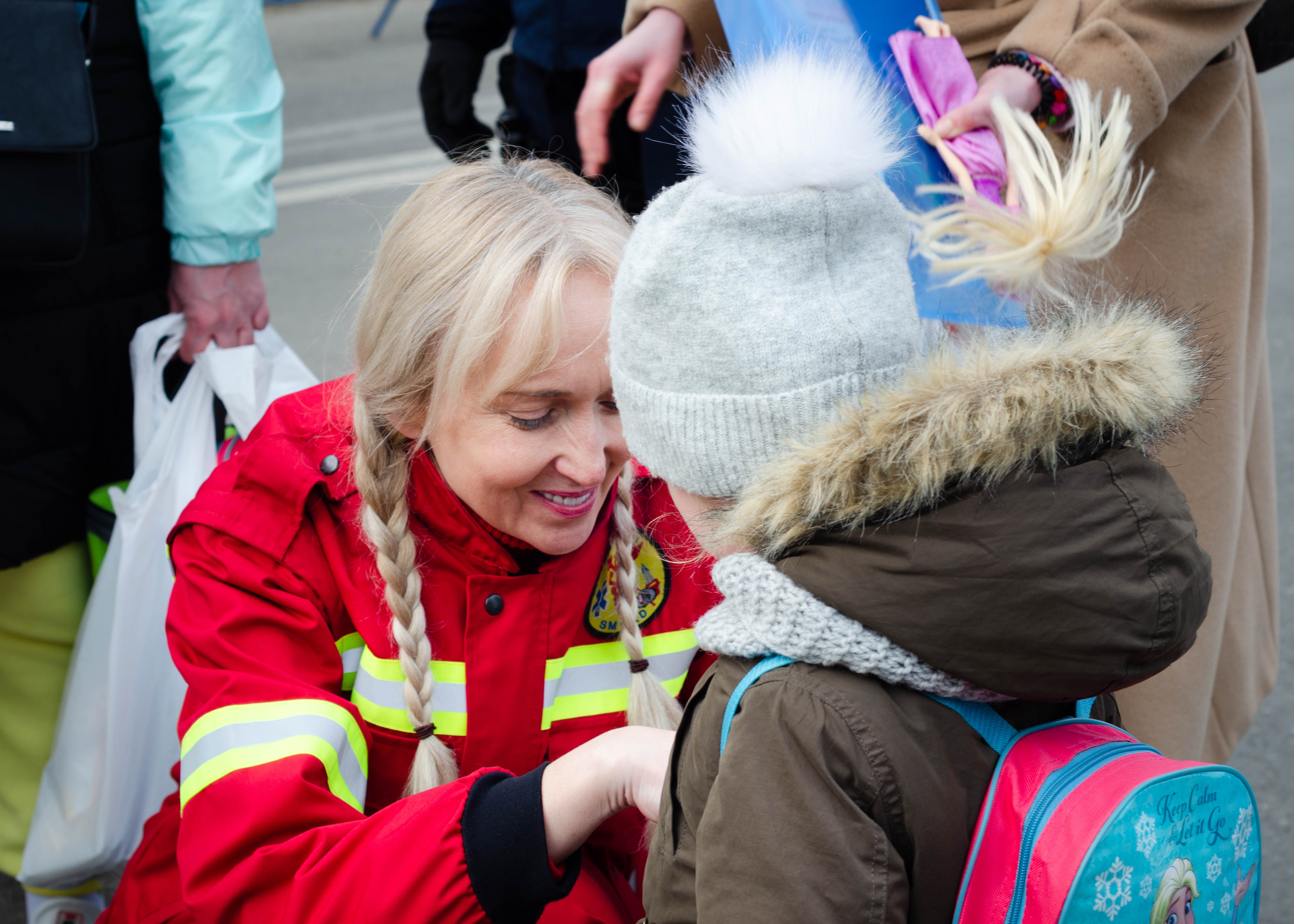 Woman in red jacket helping a young girl