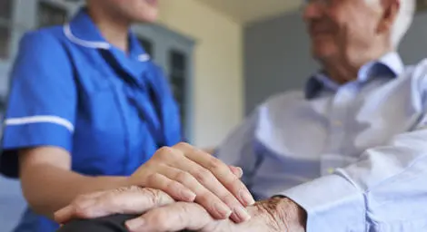 Social carer holding older man's hand