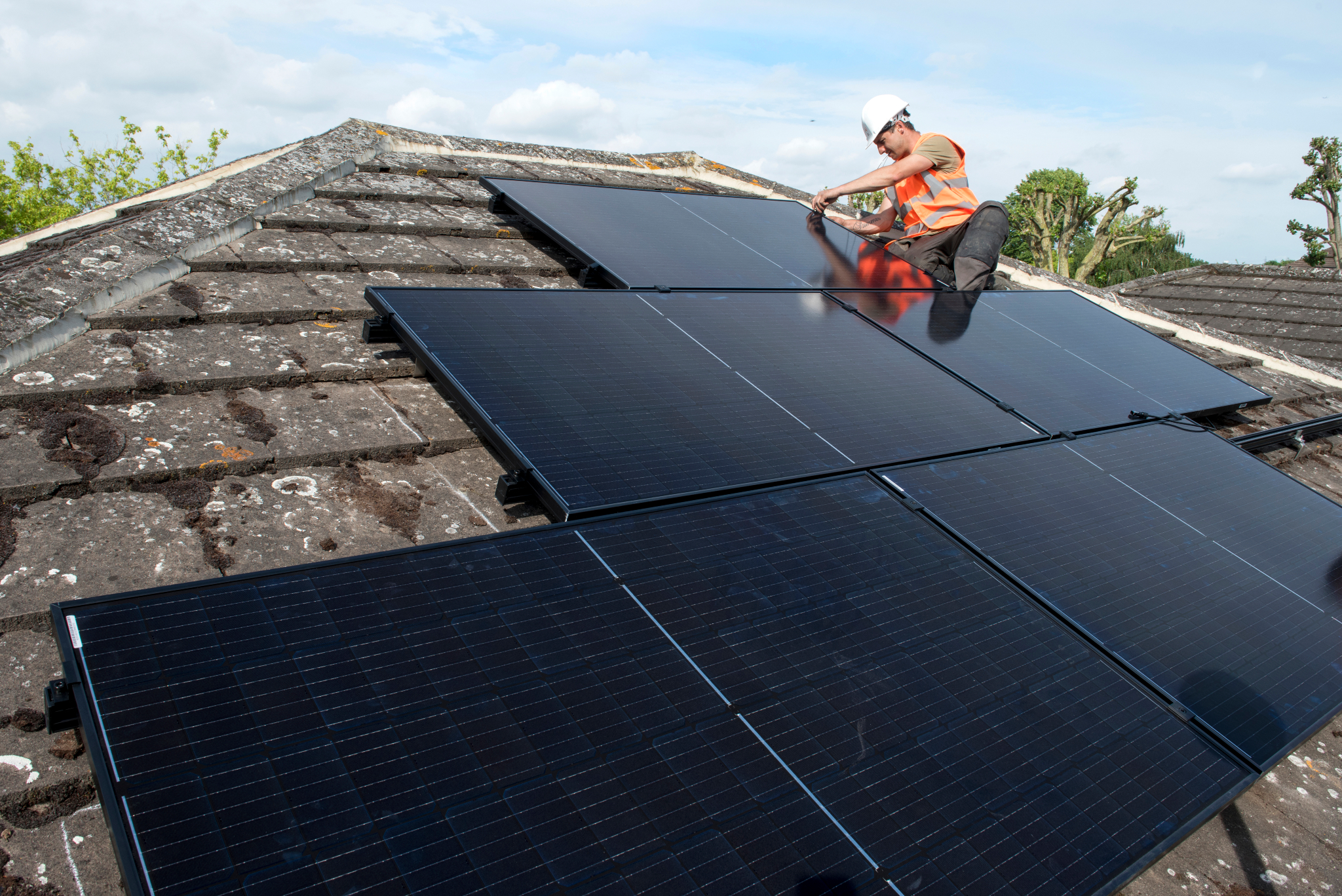 an engineer installs solar panels on the roof of a house