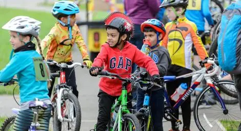 Five children in colourful clothes on bicycles taking a cycling course