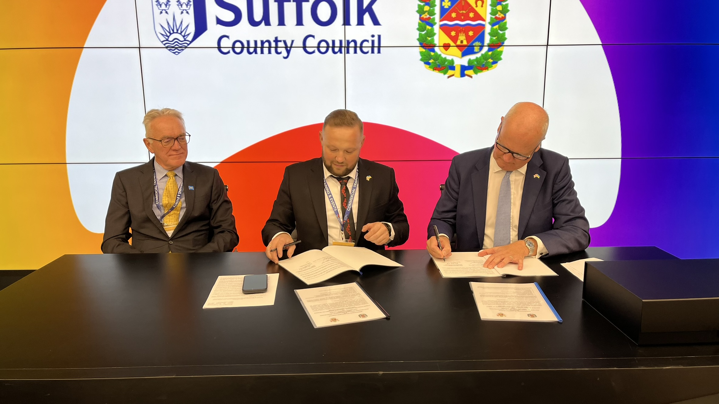 Three people signing a Memorandum of Understanding: Mark Pendlington, Volodymyr Kohut, and Councillor Matthew Hicks