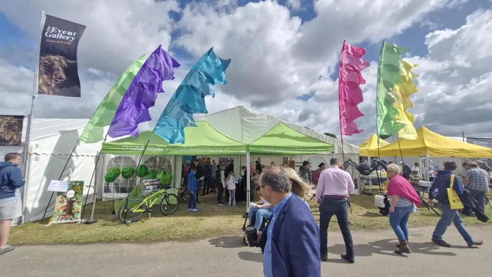 the outside of the tent with brightly coloured flags and people walking in