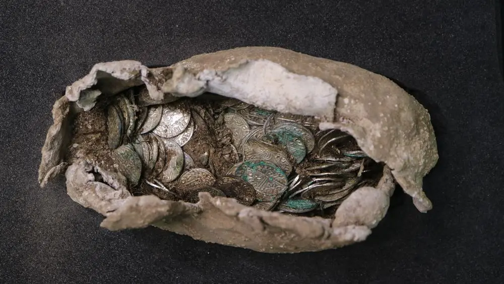 a cloth and lead sack slightly open to reveal silver coins inside